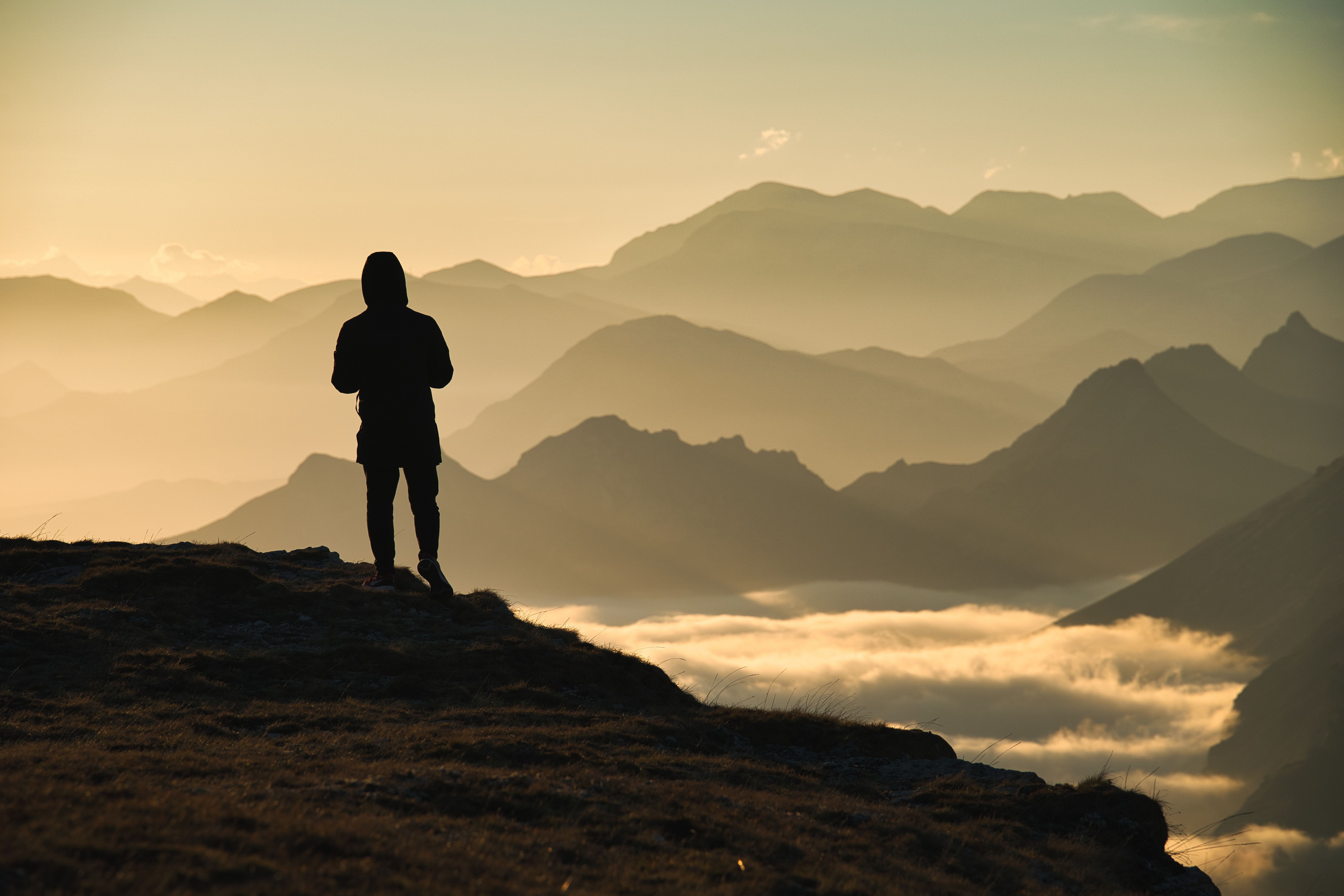 A man alone on a ridgeline above the clouds at sunrise